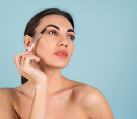 close-up-beauty-portrait-of-a-woman-with-perfect-skin-and-natural-makeup-full-nude-lips-holding-an-eyebrow-brush
