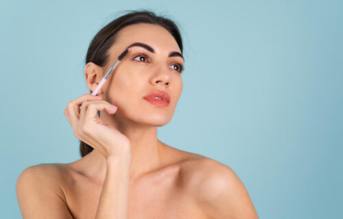 close-up-beauty-portrait-of-a-woman-with-perfect-skin-and-natural-makeup-full-nude-lips-holding-an-eyebrow-brush