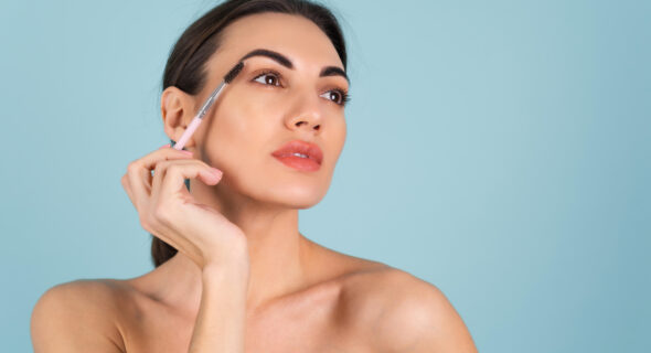 close-up-beauty-portrait-of-a-woman-with-perfect-skin-and-natural-makeup-full-nude-lips-holding-an-eyebrow-brush