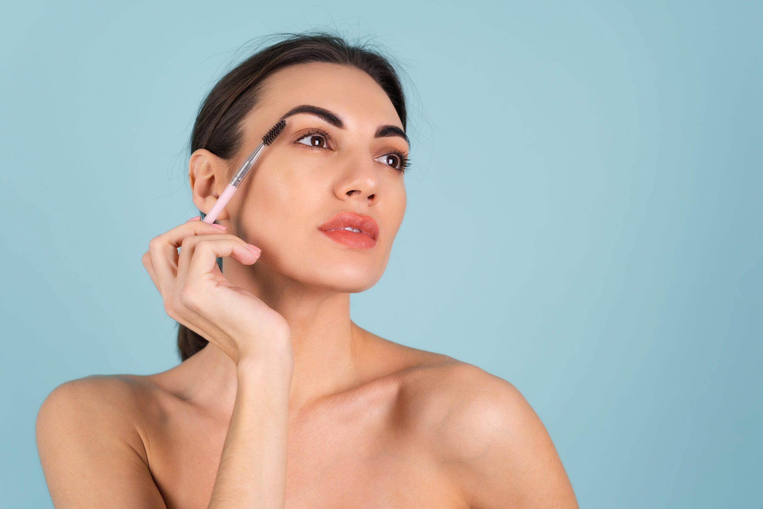 close-up-beauty-portrait-of-a-woman-with-perfect-skin-and-natural-makeup-full-nude-lips-holding-an-eyebrow-brush
