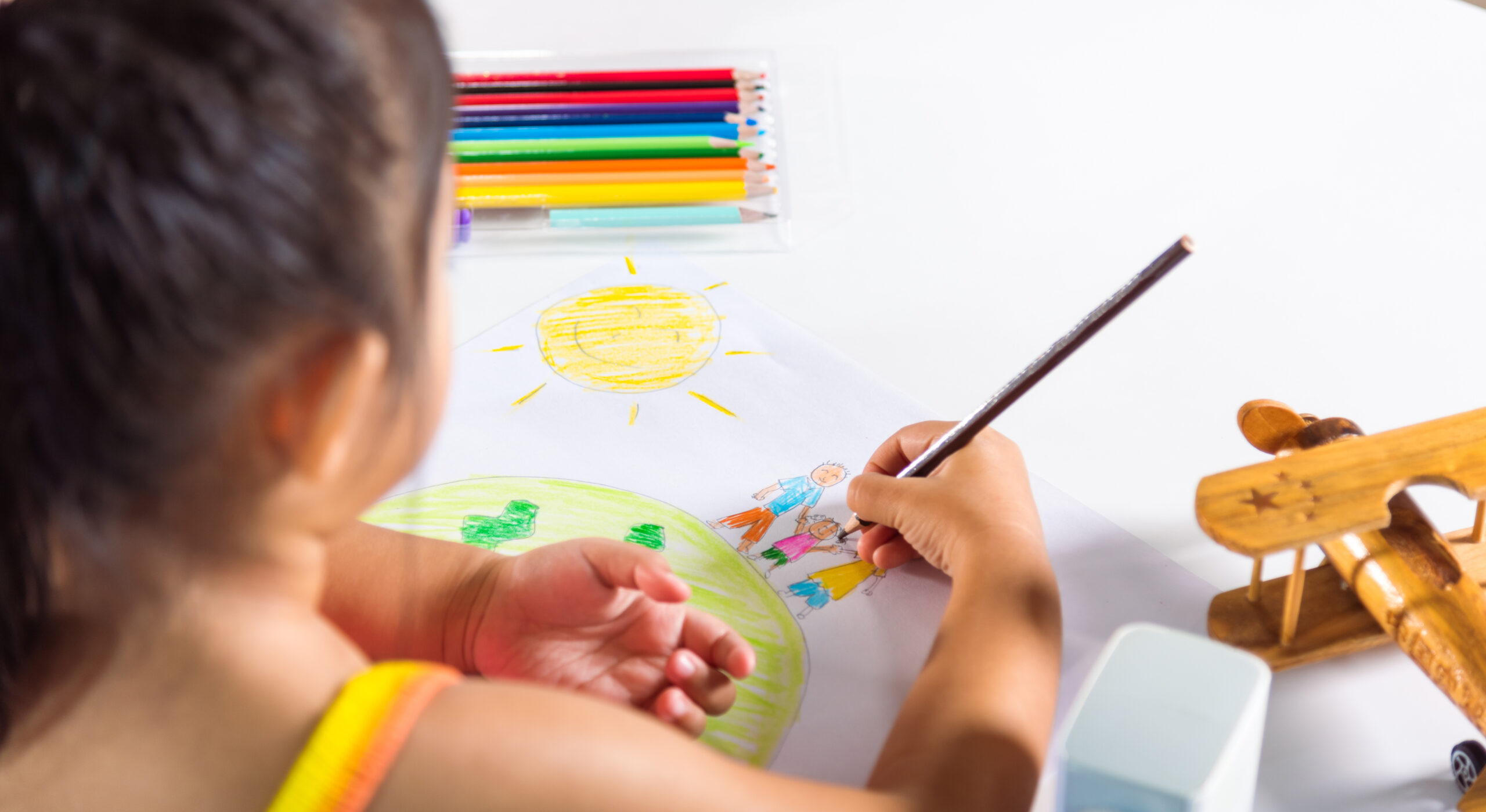 happy-child-little-girl-colorful-drawing-family-standing-hold-hands-on-planet-earth-on-paper-asian-cute-kid-preschooler-sit-on-table-smiling-she-draw-picture-with-pencil-at-home-earth-day-concept